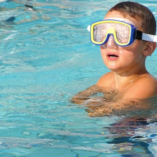 a kid in a pool with a mask