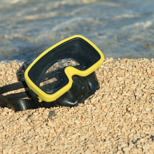 a scuba diving mask on the sand